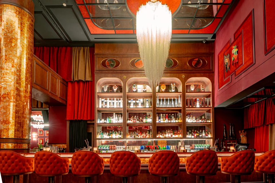 Glowing backbar under long chandelier
