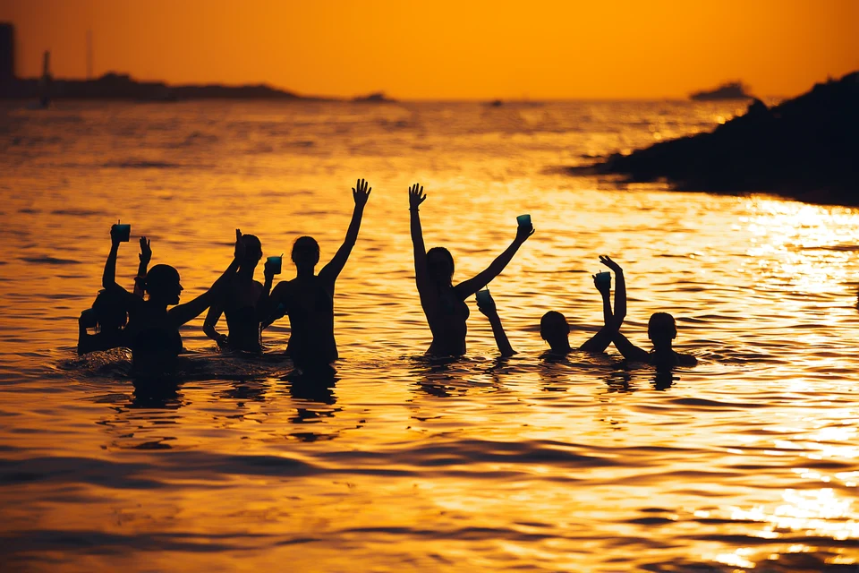 Swimmers raising arms at golden sunset