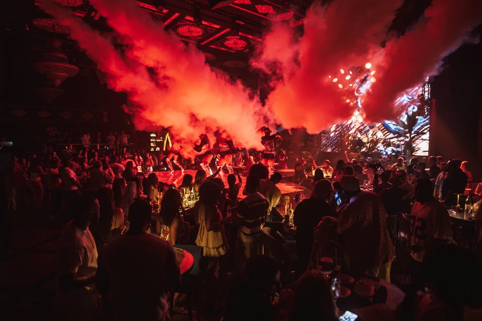 Red smoke jets above packed dancefloor