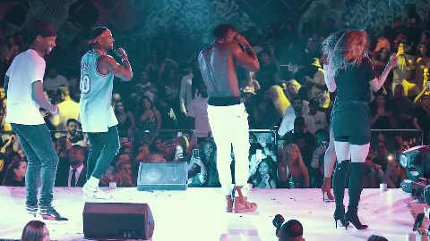 Performers and dancers on a bright concert stage.