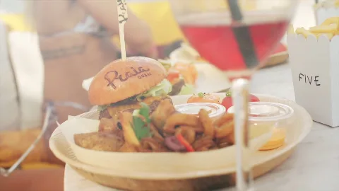 A plated burger and side dishes at PRAIA.